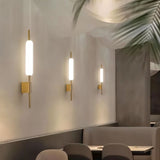 "Modern wall lamps with cylindrical glass diffusers and iron frames in a contemporary commercial space."