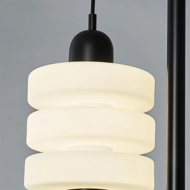 "Close-up of the layered frosted glass diffuser with a black iron top on a modern pendant light."