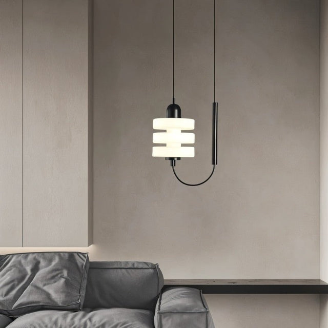 "Modern pendant light with layered frosted glass diffuser and black iron frame, hanging in a living room above a sofa."