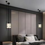 "Pair of modern pendant lights with layered frosted glass diffusers and black iron frames, flanking a bed in a bedroom."