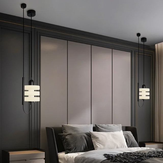 "Pair of modern pendant lights with layered frosted glass diffusers and black iron frames, flanking a bed in a bedroom."