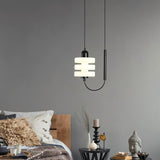 "Modern pendant light with a layered frosted glass diffuser and black iron frame, hanging in a bedroom."