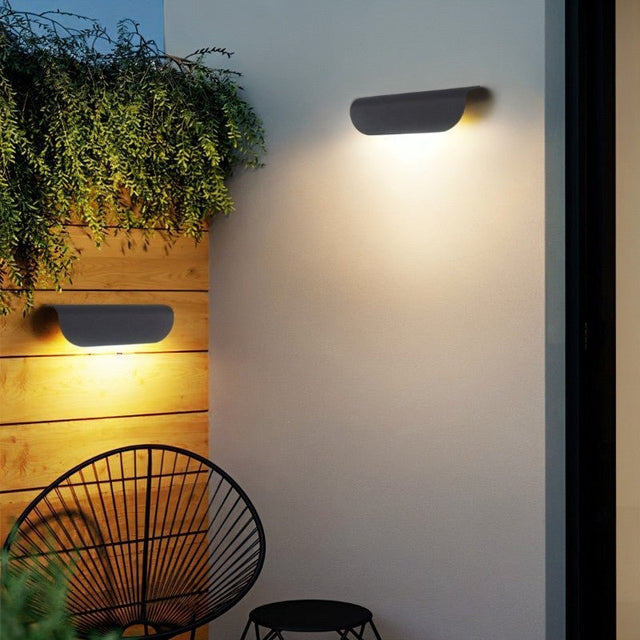 "Sleek aluminum outdoor lamp with a contemporary half-cylinder design, providing a soft glow for patios and modern outdoor spaces."