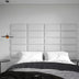 Upholstered wall panel headboard in light gray with quilted rectangular sections in a modern bedroom setting.