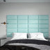 Turquoise upholstered wall panels with quilted sections installed as a bedroom headboard above a bed with white pillows and dark bedding.