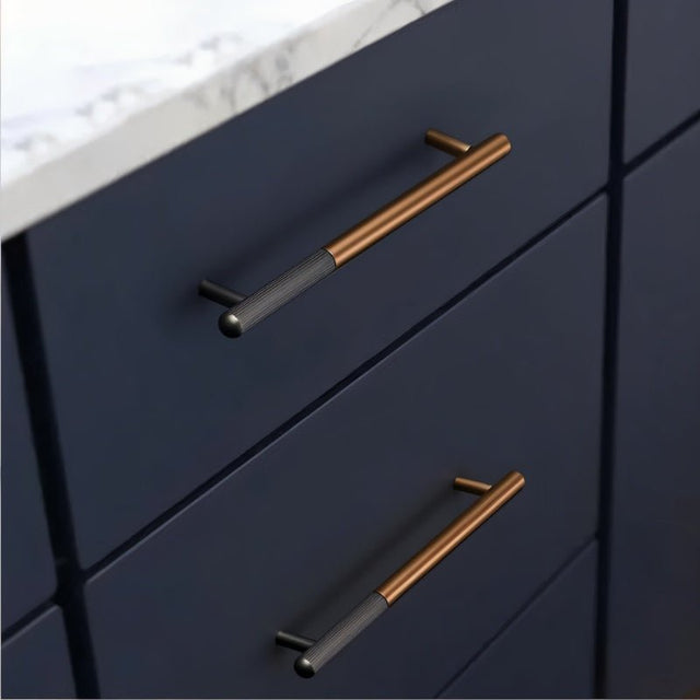 "Two minimalist aluminum pull bars on dark blue kitchen cabinets with a white marble countertop."