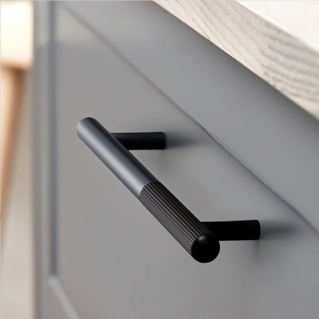 "A minimalist aluminum pull bar handle on a grey contemporary cabinet."