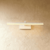 Linear bathroom vanity light with bronze finish and white acrylic shade mounted above decorative mirror in lifestyle setting.