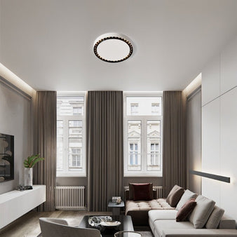 "In this living room, the Nival ceiling light features a circular, intricate design, made from acrylic and aluminum, offering stylish illumination with white and dark accents for modern interiors."