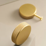 "Close-up of a gold brass cylindrical knob with a knurled texture."