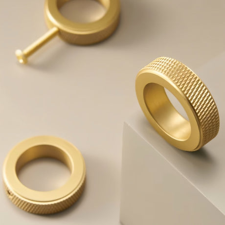 "Close-up of three gold brass cylindrical knobs with knurled texture on a gray surface, showcasing a modern design."