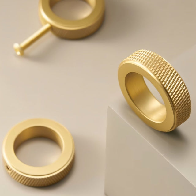 "Close-up of three gold brass cylindrical knobs with knurled texture on a gray surface, showcasing a modern design."