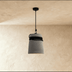Three gray cone-shaped pendant lights with different trim details hanging against a white wall, styled with decorative object