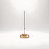 Pendant light with amber glass dome and black cord against white background.