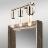 "Brushed nickel 3-light industrial wall sconce with a minimalist design above a mirror."