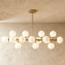 Mid-century modern brass chandelier with 9 spherical frosted glass shades on white background, front view.