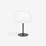 "A white table lamp with a layered, wave-like diffuser, isolated on a white background."