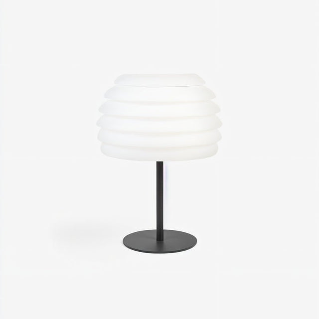 "A white table lamp with a layered, wave-like diffuser, isolated on a white background."