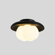 "A ceiling light with a black travertine frame and a cloud-shaped, white acrylic shade against a gray background."