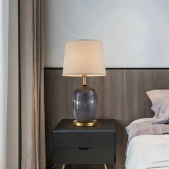 "Table lamp with marble ceramic base and fabric shade on a bedside table in a bedroom."