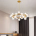 Modern brass chandelier with clear glass globe shades hanging in a contemporary bedroom with dark curtains.