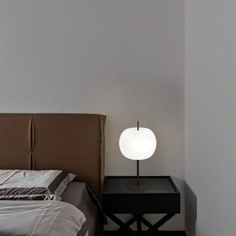 "Minimalist table lamp with frosted glass shade on a bedside table in a cozy bedroom, featuring an aluminum and iron base for soft illumination."