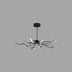 "A slightly angled view of a modern black chandelier with twelve curved branches, each tipped with a white light, against a gray background."