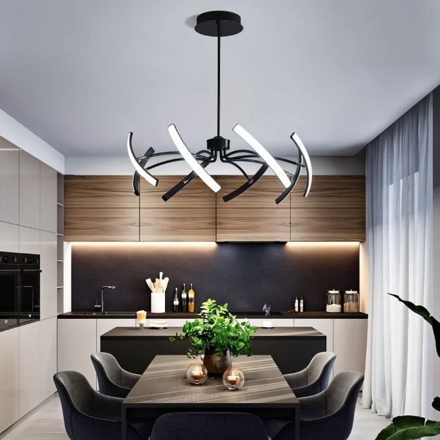 "A black chandelier with six curved arms, each tipped with a white light, installed above a dining table in a modern kitchen."