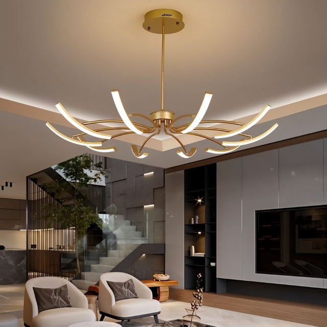 "A gold chandelier with twelve curved branches, each tipped with a white light, installed in a modern living room, viewed from a slightly angled perspective."