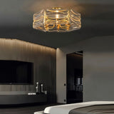 "A modern flush mount ceiling light with a geometric glass shade and gold frame, installed in a contemporary bedroom."