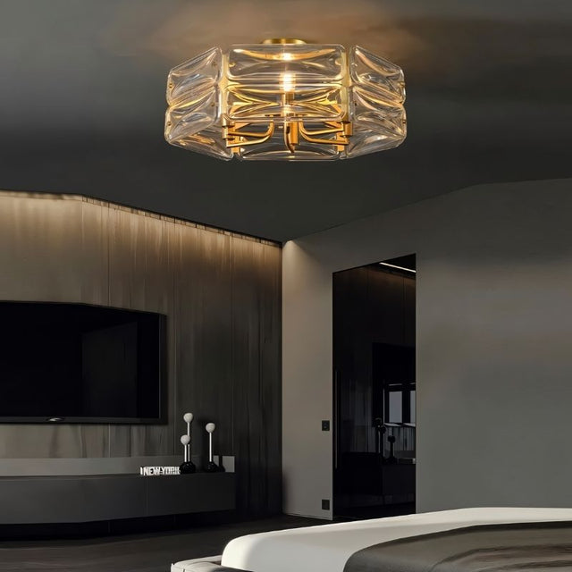 "A modern flush mount ceiling light with a geometric glass shade and gold frame, installed in a contemporary bedroom."