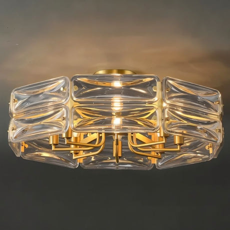 "A modern flush mount ceiling light with a geometric glass shade and gold frame, illuminated against a dark background."
