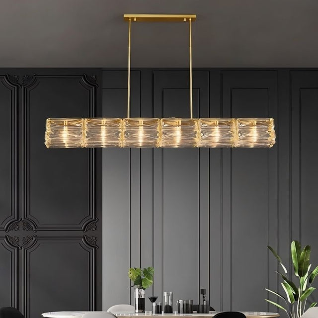 "Linear chandelier with gold frame and textured glass shades over a dining table."