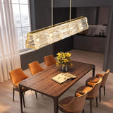 "Modern linear light fixture over a dining table with orange chairs."