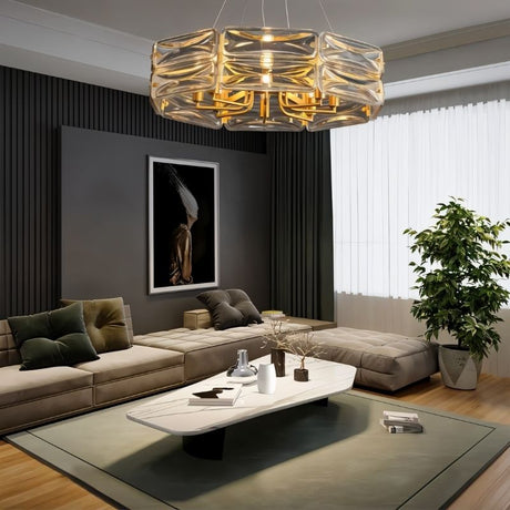 "A modern round chandelier with a geometric glass shade and gold frame, hanging in a living room with a sectional couch and artwork."