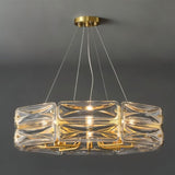 "A modern round chandelier with a geometric glass shade and gold frame, suspended against a gray background."