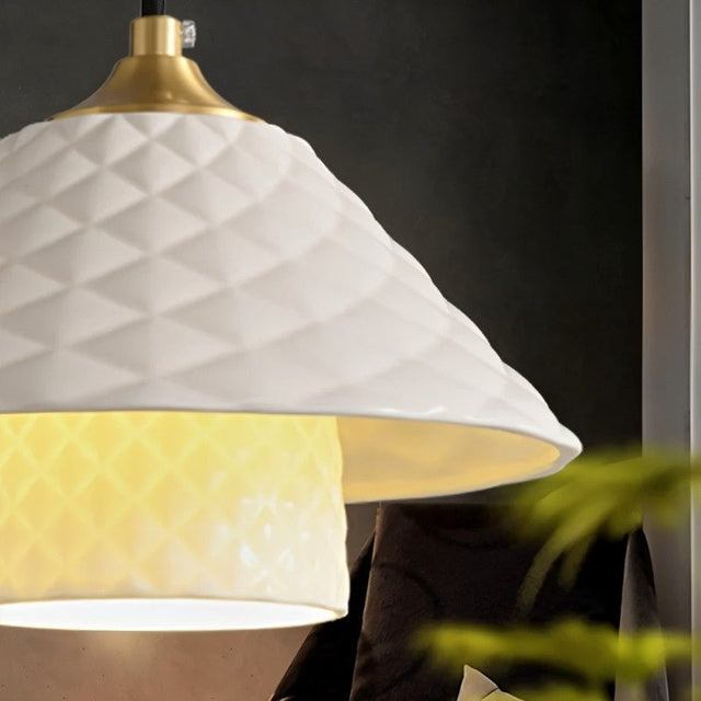 "Close-up of a modern chandelier's textured ceramic shade with a brass fitting."