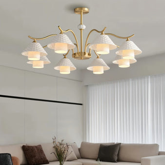 "A modern chandelier with brass arms and textured ceramic shades in a living room."