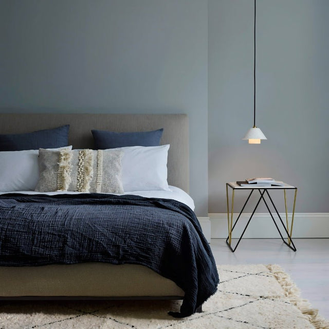 "A modern pendant light with a textured ceramic shade in a bedroom setting."