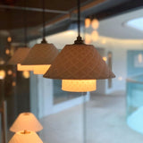 "A group of modern pendant lights with textured ceramic shades hanging in a room."
