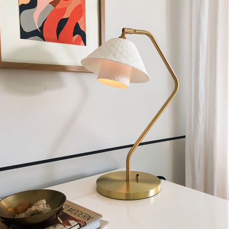 Stylish Ocris Table Lamp on a white desk with brass finish and quilted ceramic shade, enhancing indoor lighting decor.