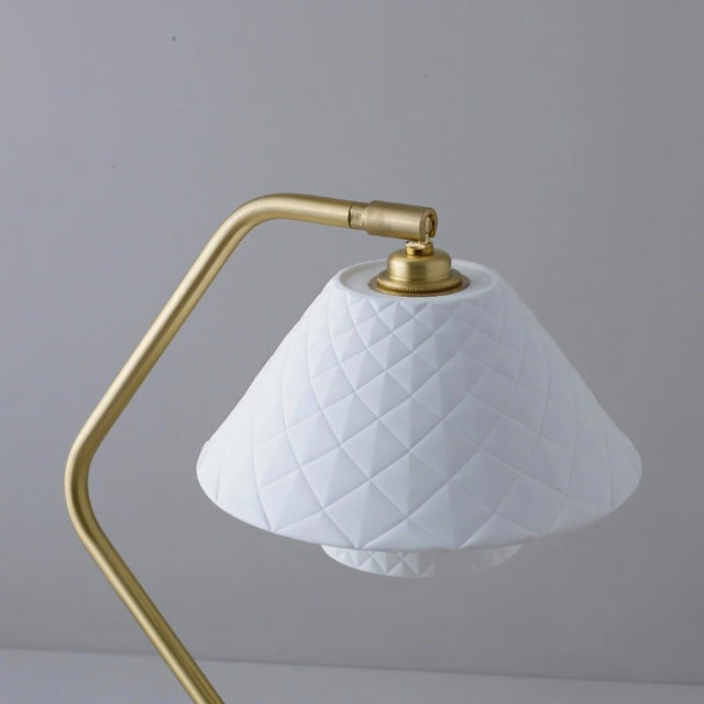 Detail view of Ocris Table Lamp's white quilted ceramic shade and brass fixture, highlighting elegant indoor lighting design.