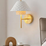 "A modern brass wall lamp with a textured diamond pattern ceramic shade."