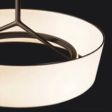 "A close-up view of a pendant light showing the texture of the wide, white fabric drum shade and the sleek frame."