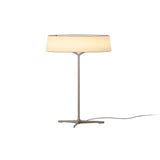 "A modern table lamp with a light-colored fabric drum shade and a sleek, light-colored stand with a Y-shaped base."