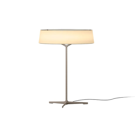"A modern table lamp with a light-colored fabric drum shade and a sleek, light-colored stand with a Y-shaped base."