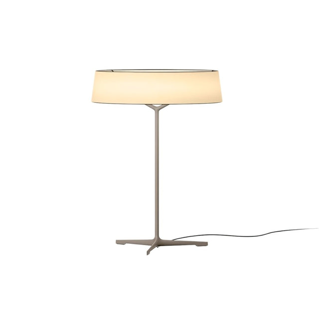 "A modern table lamp with a light-colored fabric drum shade and a sleek, light-colored stand with a Y-shaped base."
