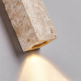 "Close-up of a minimalist rectangular travertine wall lamp, highlighting the natural stone texture and the soft, directional light it emits."