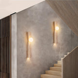 "Pair of minimalist rectangular travertine wall lamps with frosted globe lights, mounted on a textured wall alongside a modern staircase, providing soft ambient lighting."