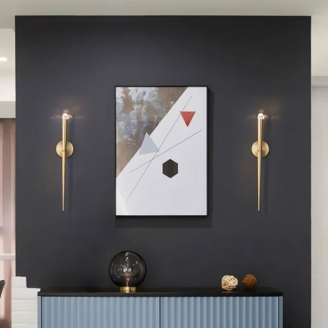 "Pair of modern gold wall lamps with crystal accents flanking a framed abstract art piece in a contemporary living room."
